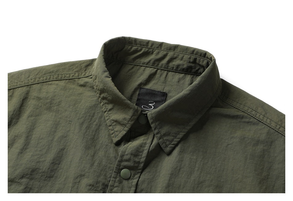 Close-up of the dark olive shirt's pointed collar, neck label, stitching, and front snap buttons.