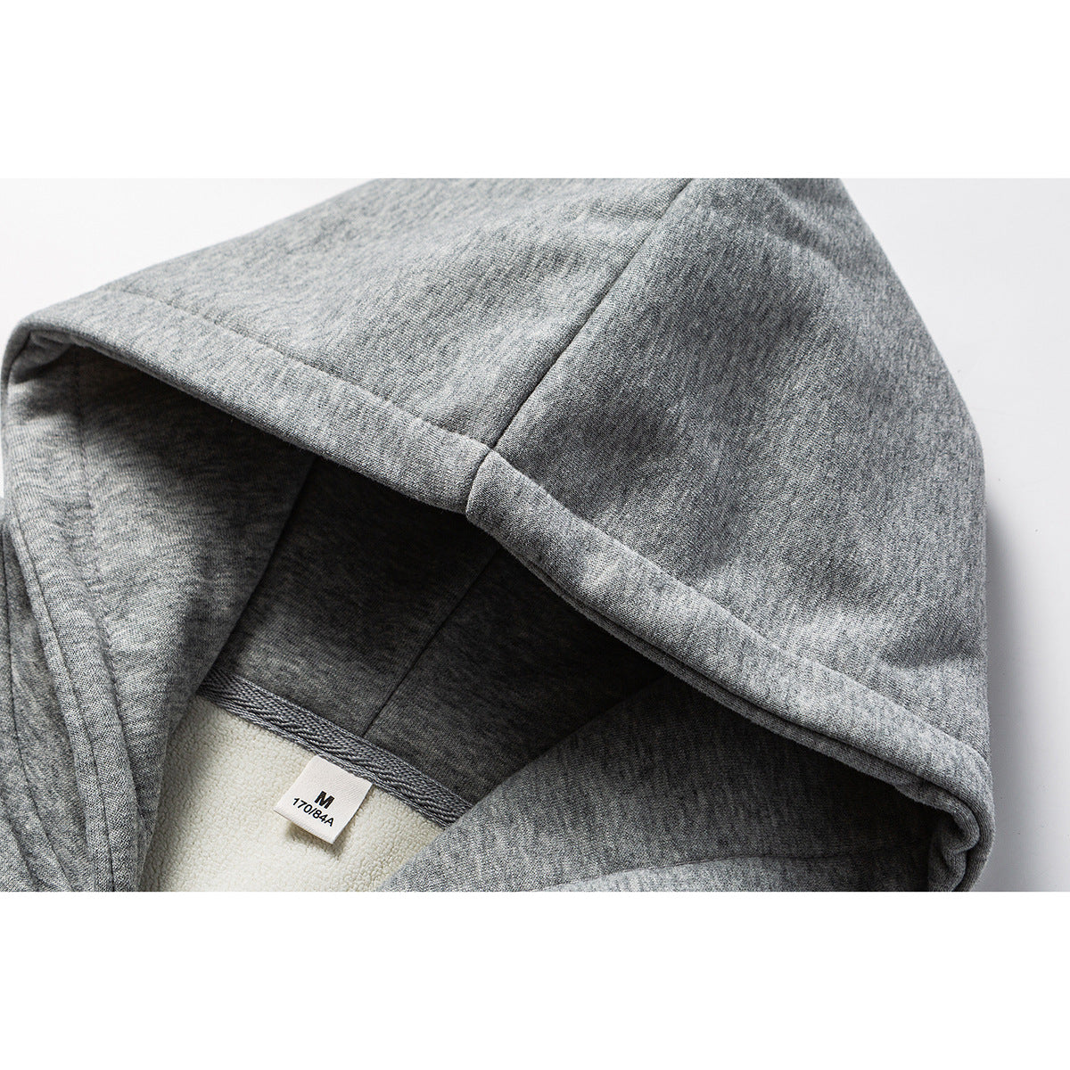Close-up of a heather-gray hoodie's hood lining and seam, with a visible M size label.