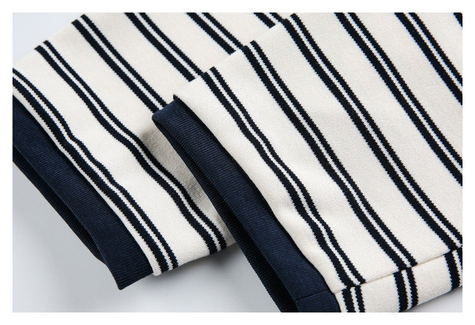 Close-up of a striped ivory garment with dark navy ribbed cuffs and hem.