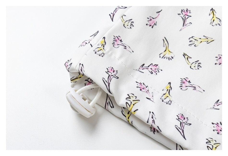 Close-up of a white floral-print garment with an adjustable drawcord and plastic toggle.