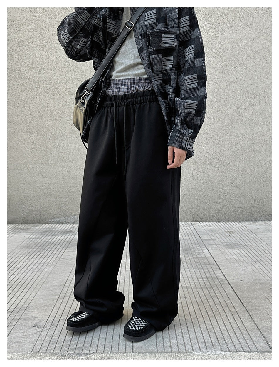 Person wearing black wide-leg drawstring pants with patterned shirt and checkered shoes, three-quarter view