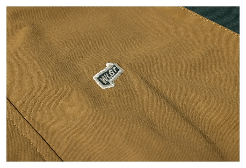Embroidered patch on the tan jacket, shown against close-up fabric and stitching.