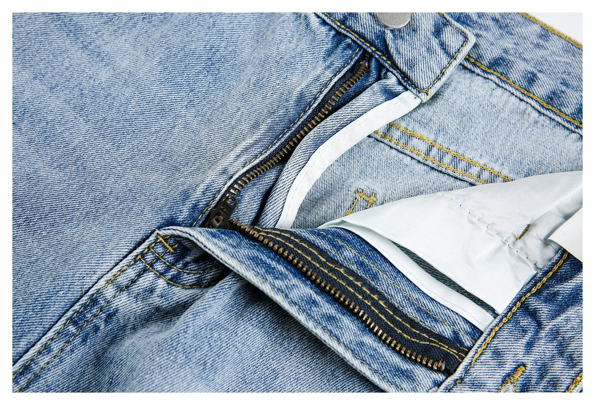 Close-up of light-wash jeans with the fly unfastened, showing the zipper and inner waistband.