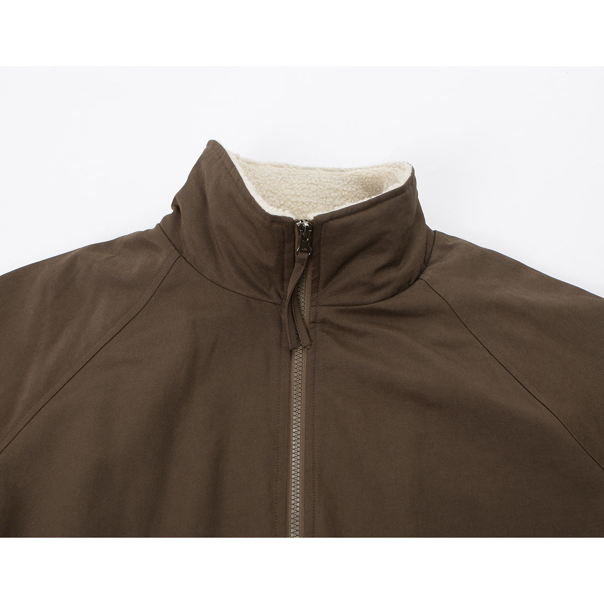 Close-up of a brown jacket's high stand collar, cream sherpa lining, and front zipper.