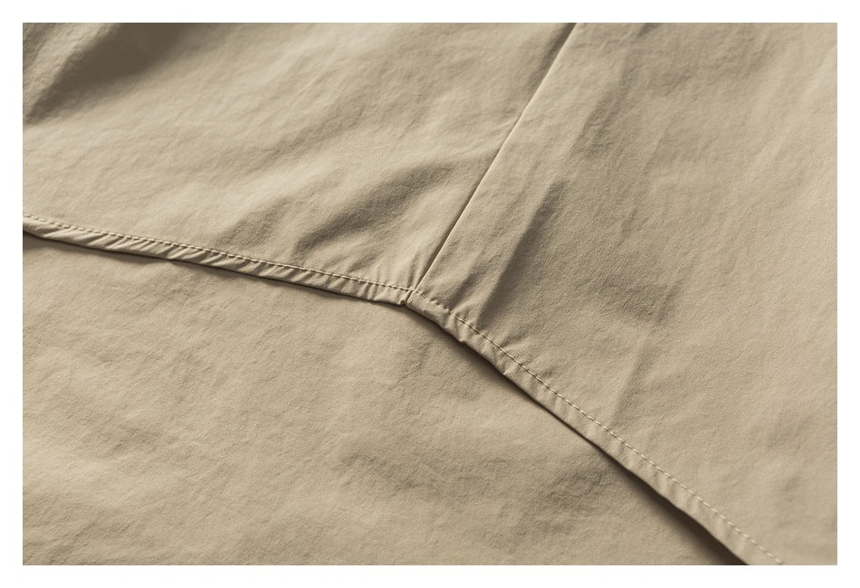 Close-up of a light tan garment showing intersecting stitched seams.