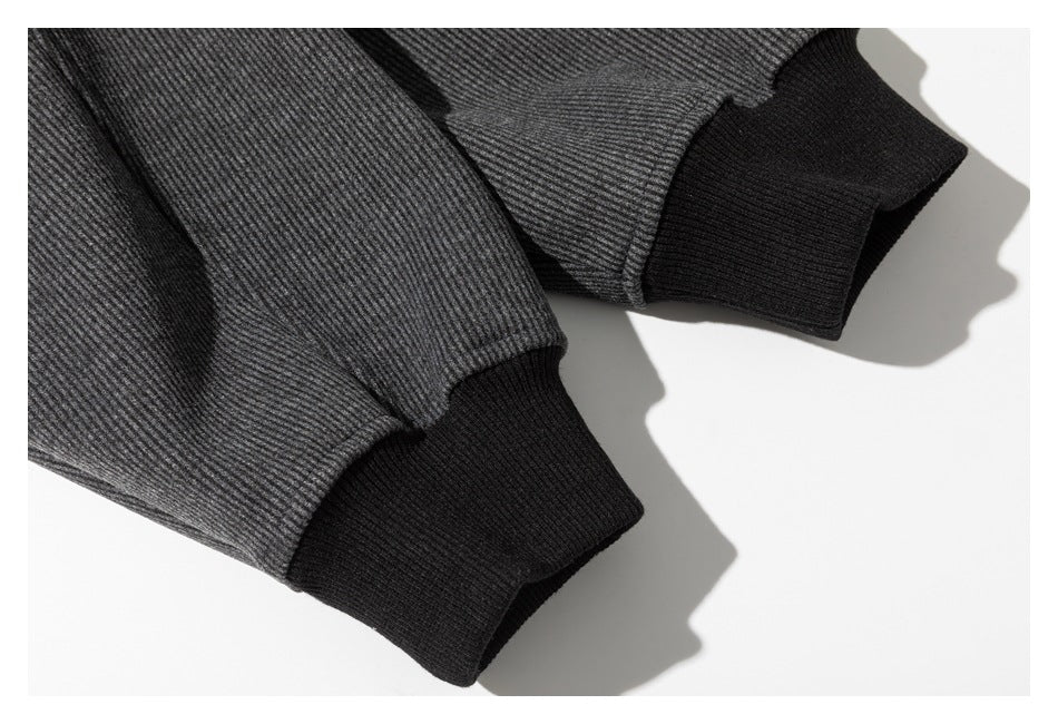 Close-up of two dark gray ribbed sleeves finished with black rib-knit cuffs.