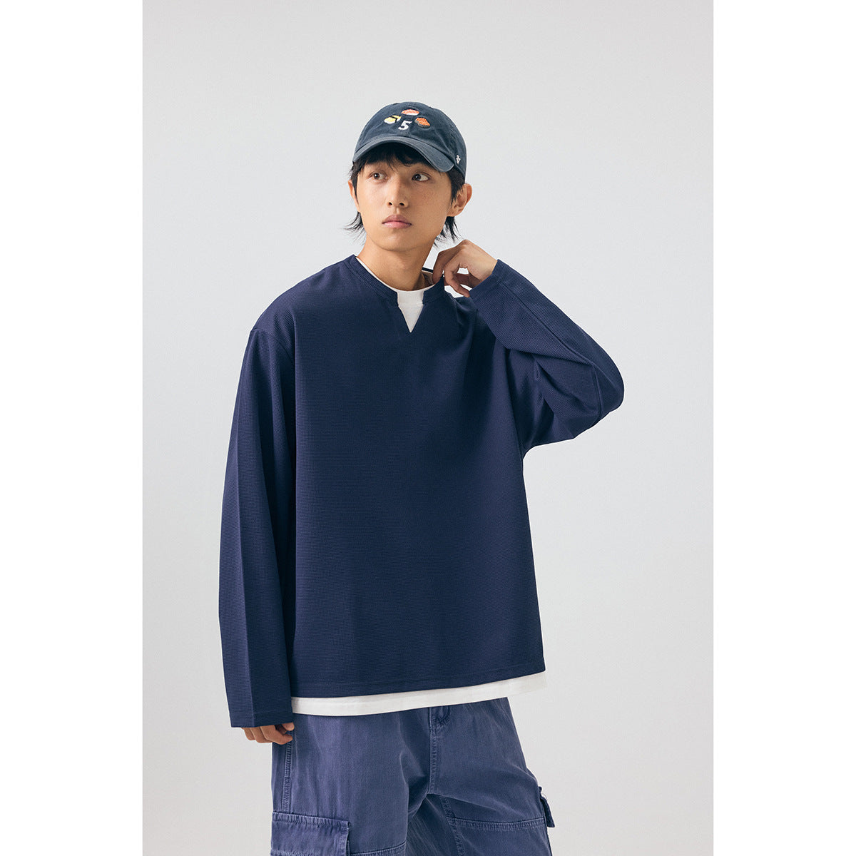 Model wearing a loose navy long-sleeve top with a split neckline and white layer underneath.