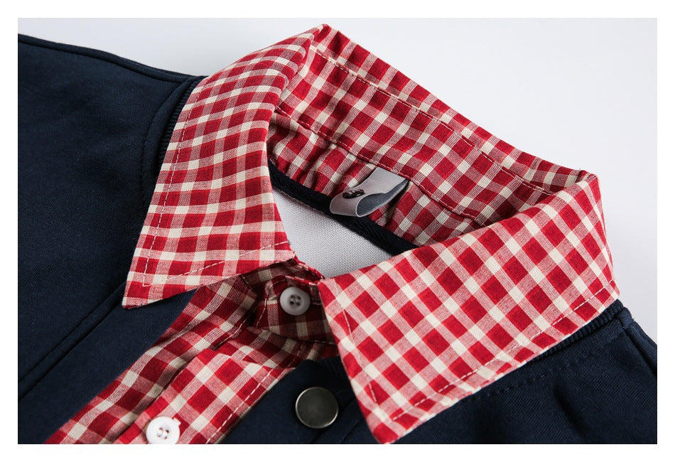 Close-up of a navy garment with a red-and-cream check collar and buttoned placket.