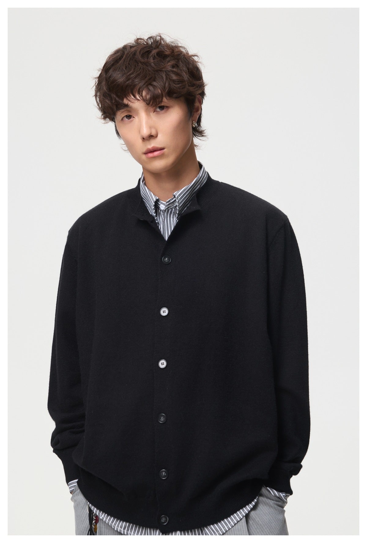 Closer view of a model wearing a black button-front cardigan over a striped shirt.