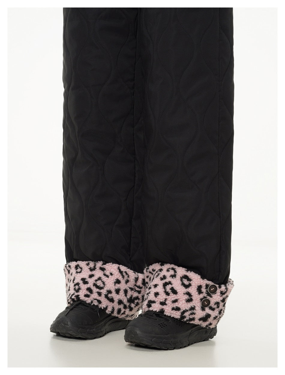 Close-up of black quilted pant legs and pink leopard-print cuffs, with two buttons on one cuff.