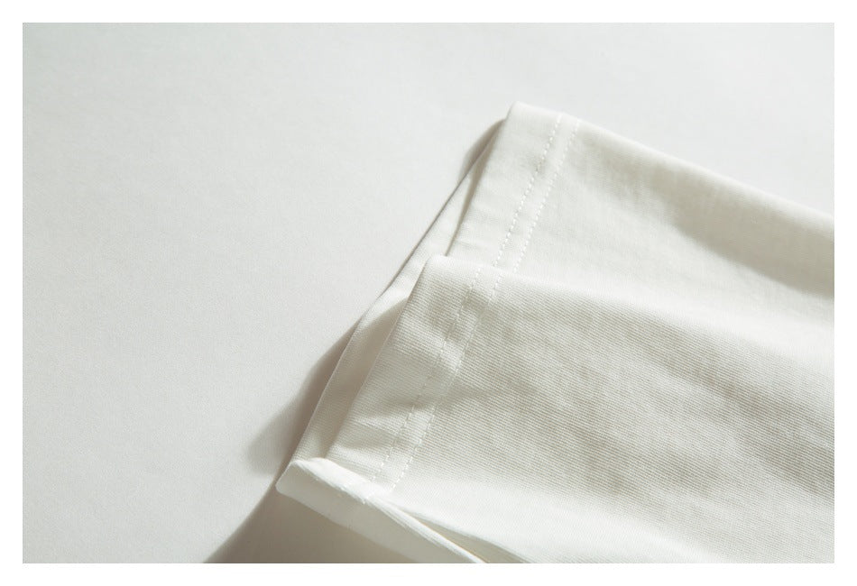 Close-up of the folded sleeve and stitched hem of an off-white T-shirt.