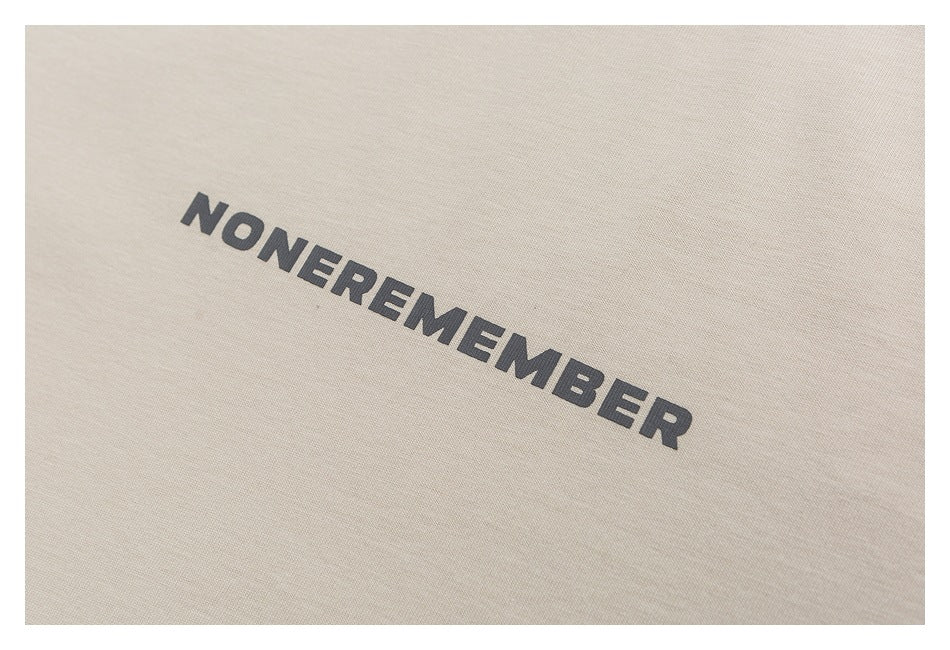 Close-up of dark lettering printed diagonally on light beige shirt fabric.