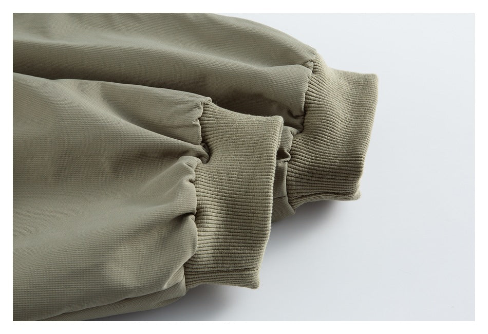 Close-up of an olive-gray jacket sleeve with a wide ribbed cuff.