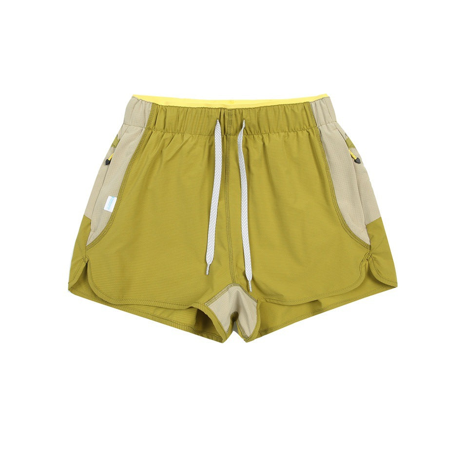 Olive green shorts with white drawstring, beige side panels and a yellow inner waistband, flat lay