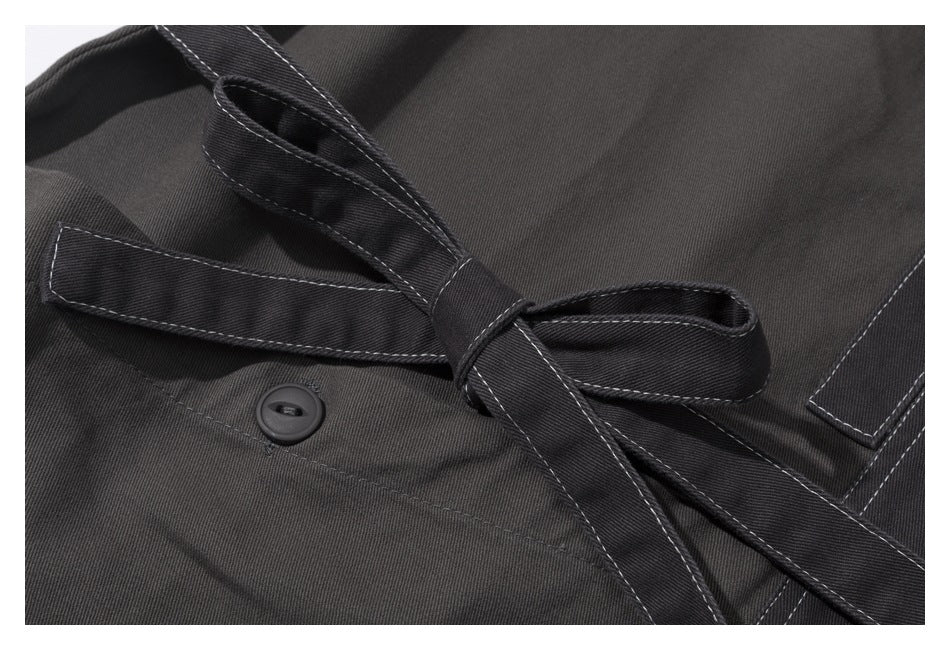 Close-up of a dark charcoal garment with a tied belt, white contrast stitching, and a dark button.