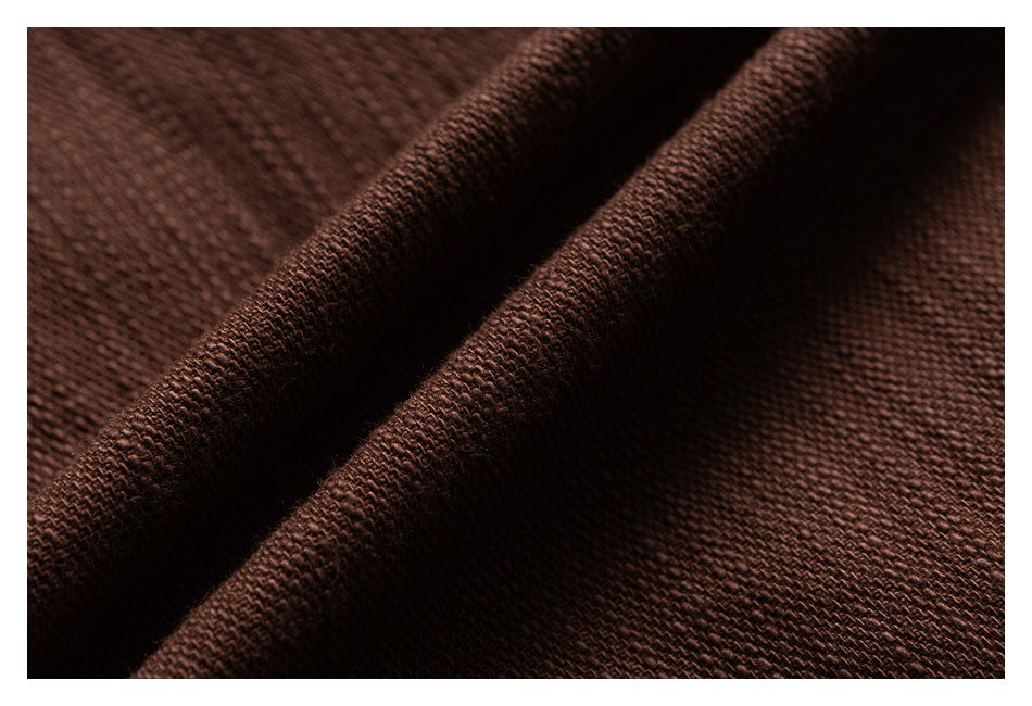 Macro view of brown garment fabric showing its woven texture and folded edge.