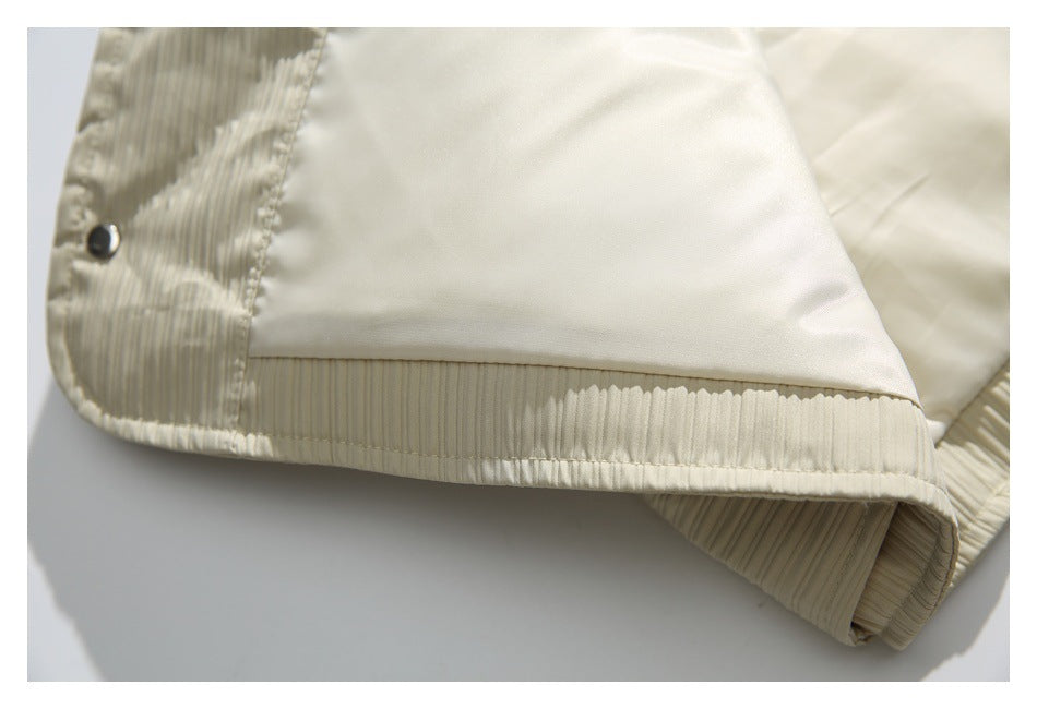 Close-up of the ivory jacket's smooth inner lining, ribbed hem, and a metal snap.