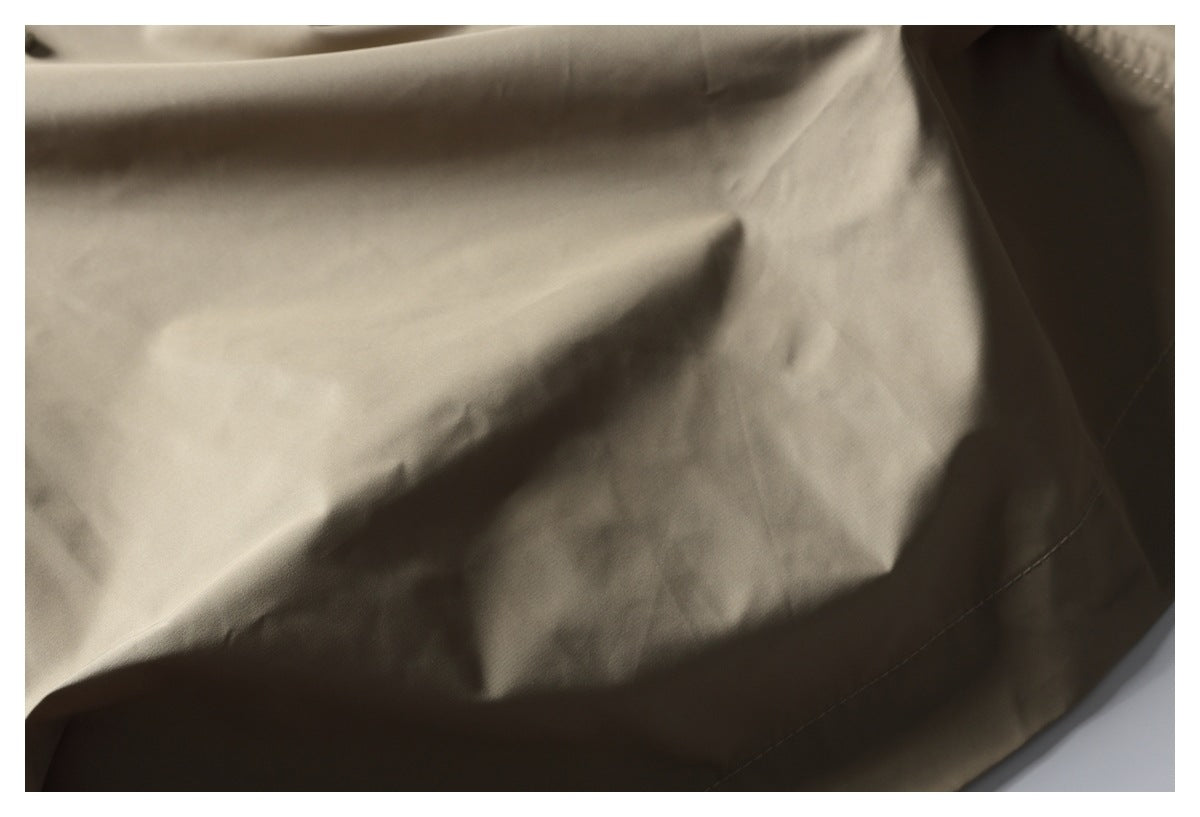 Close-up of taupe trousers showing smooth fabric and a stitched seam.