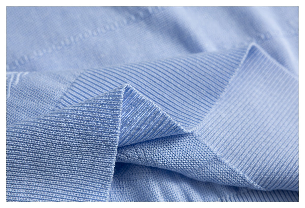 Close-up of a light blue sweater's folded ribbed cuff and knit texture.