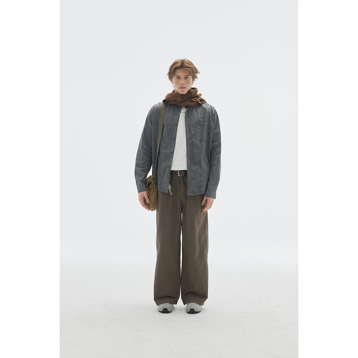 Front view of a model in dark olive wide-leg trousers and a gray button-up shirt, styled with a brown plaid scarf and