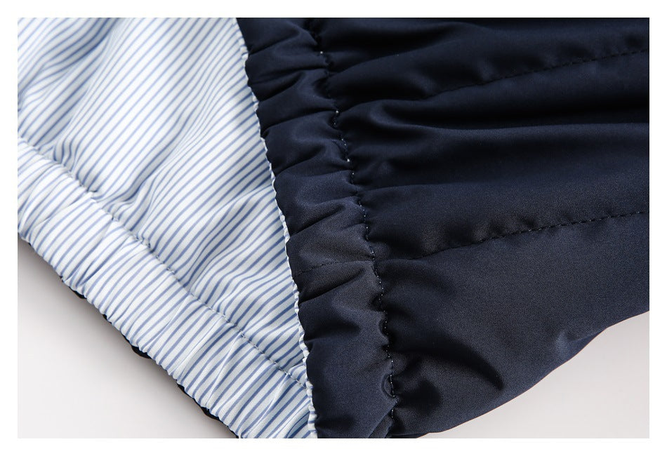 Close-up of navy quilted fabric beside white lining with thin blue stripes.