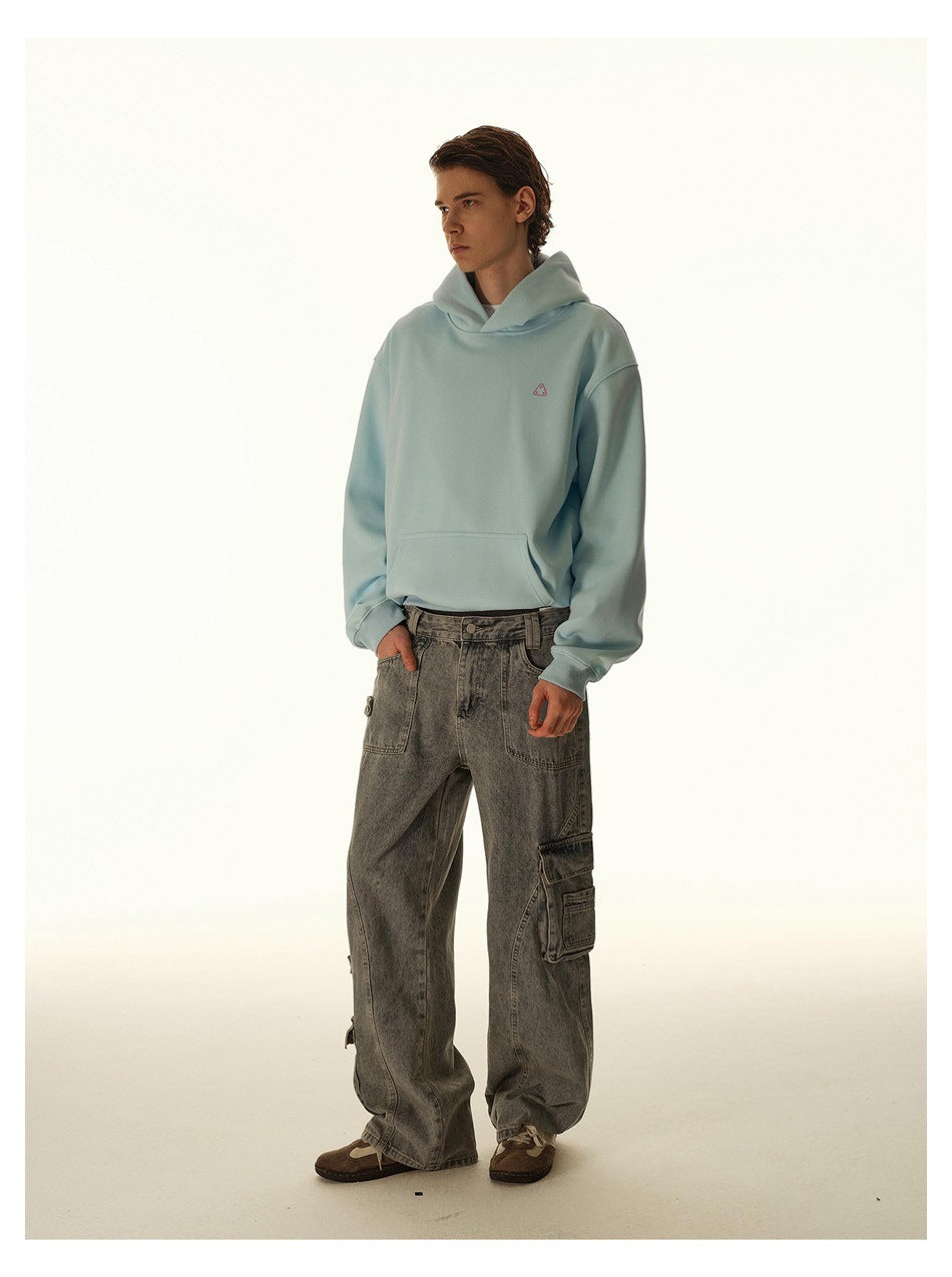 Model in a pale blue oversized hoodie and loose gray cargo jeans, standing at a slight angle.