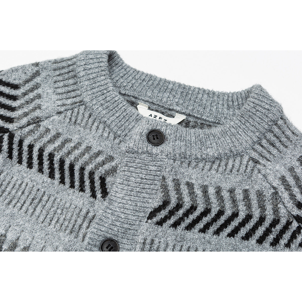 Close-up of a gray knit cardigan with a ribbed collar, black buttons, and dark geometric bands.