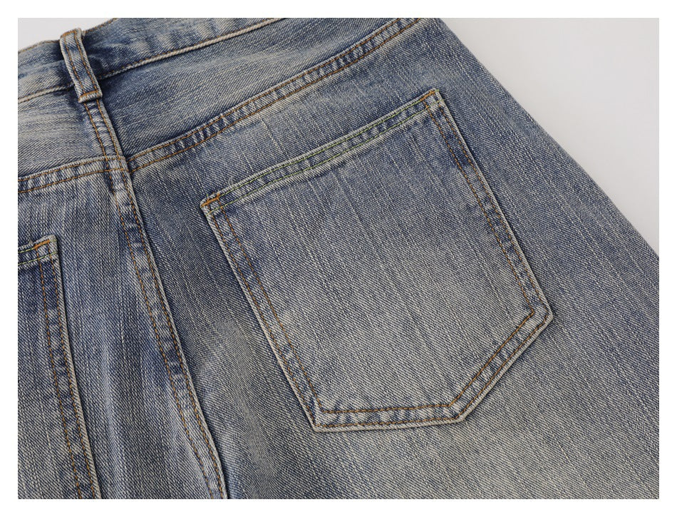 Close-up of a faded blue denim back pocket with tan contrast stitching.