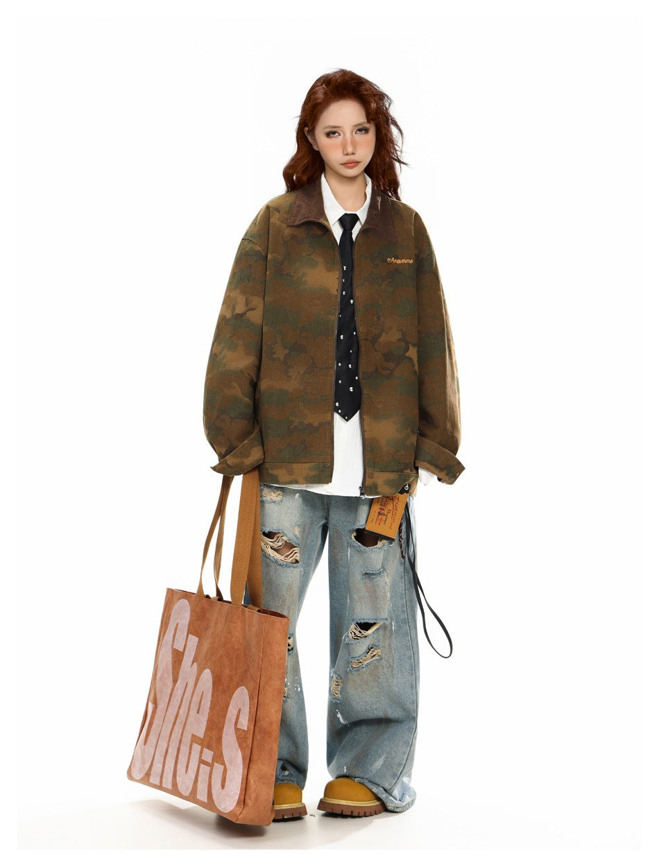 Model wearing oversized camouflage zip jacket over white shirt and tie with ripped jeans, holding a tote bag