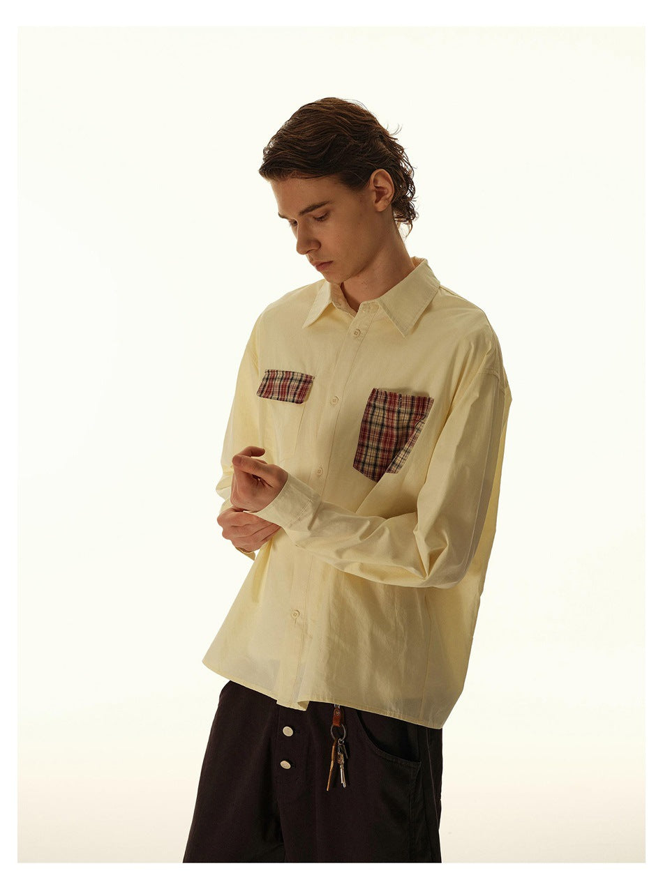 Three-quarter view of a model wearing a pale cream button-up shirt with plaid chest pockets.