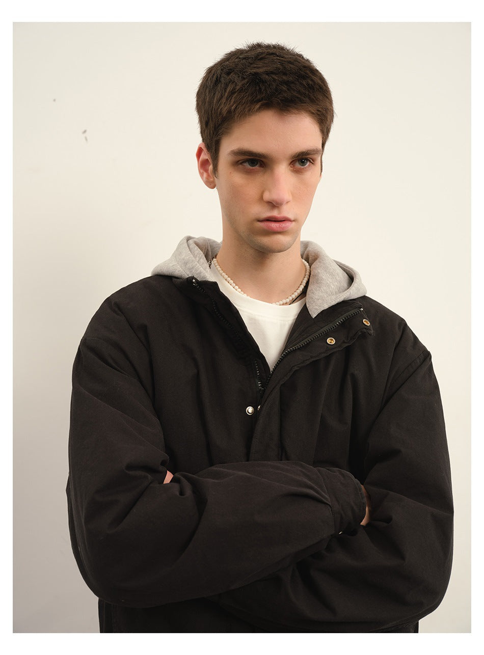 Close view of a model wearing a black jacket over a gray hooded layer, showing the collar and snap-front details.