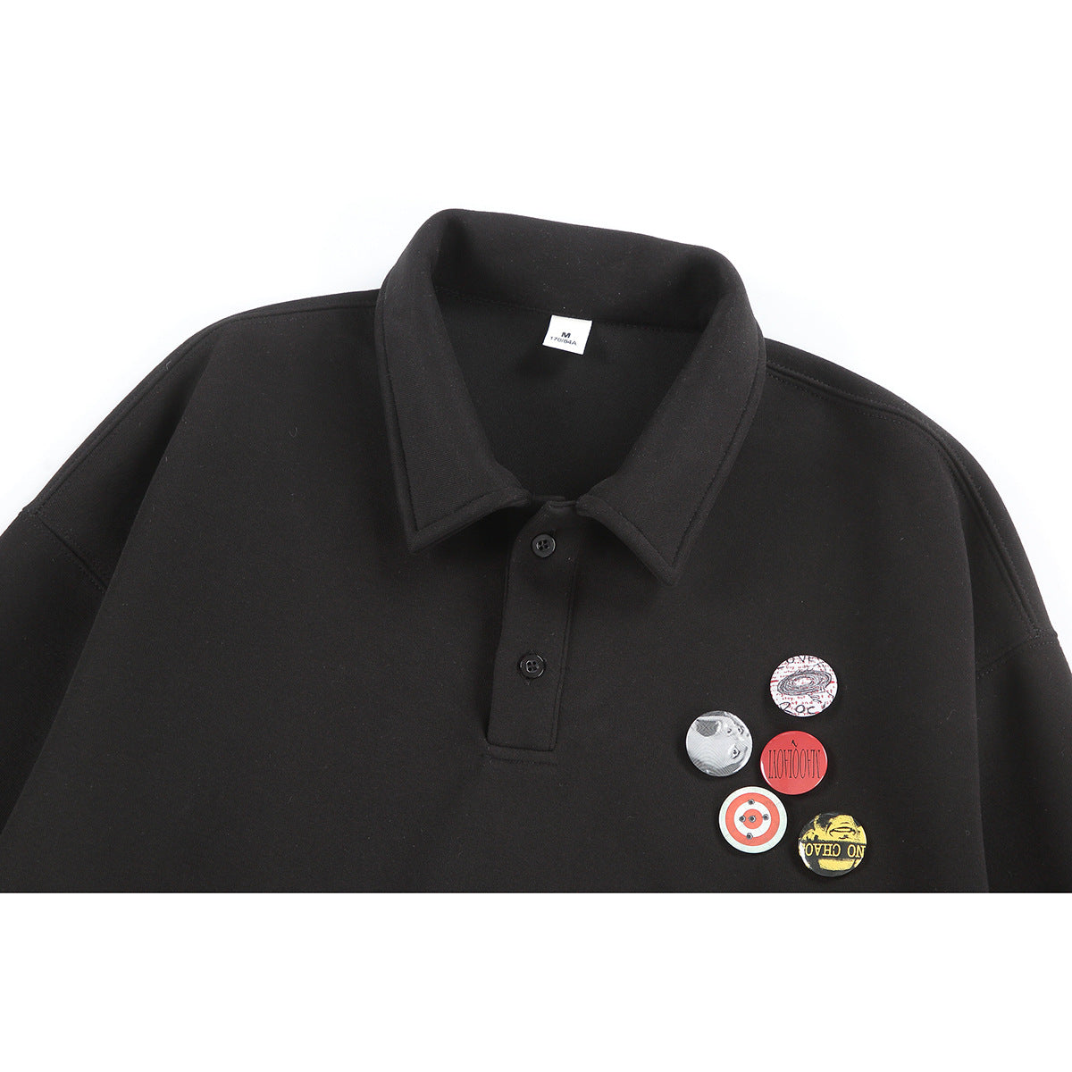 Close-up of a black collared pullover with a two-button placket and five colorful circular chest graphics.