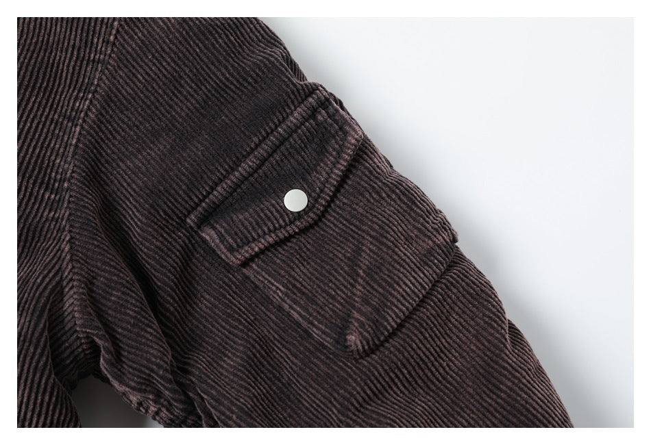 Close-up of a dark ribbed jacket sleeve with a flap pocket and round snap.