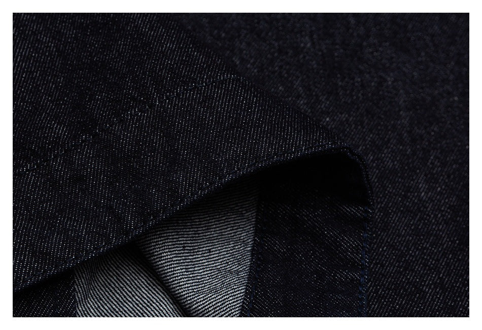 Close-up of folded dark denim showing a seam and striped reverse side.