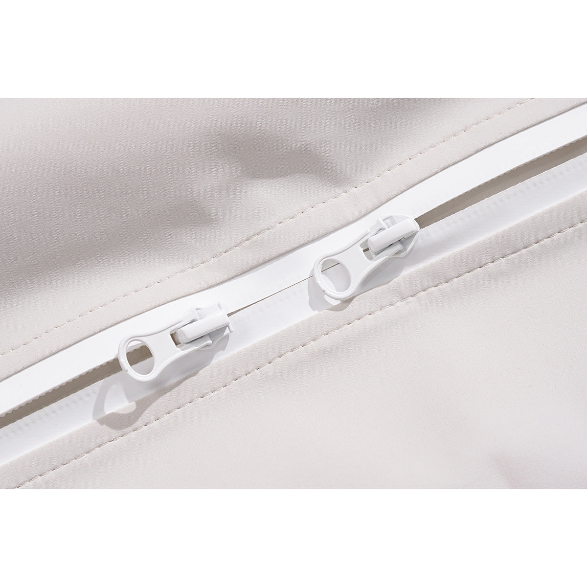 Close-up of two white zipper pulls on an off-white skirt.