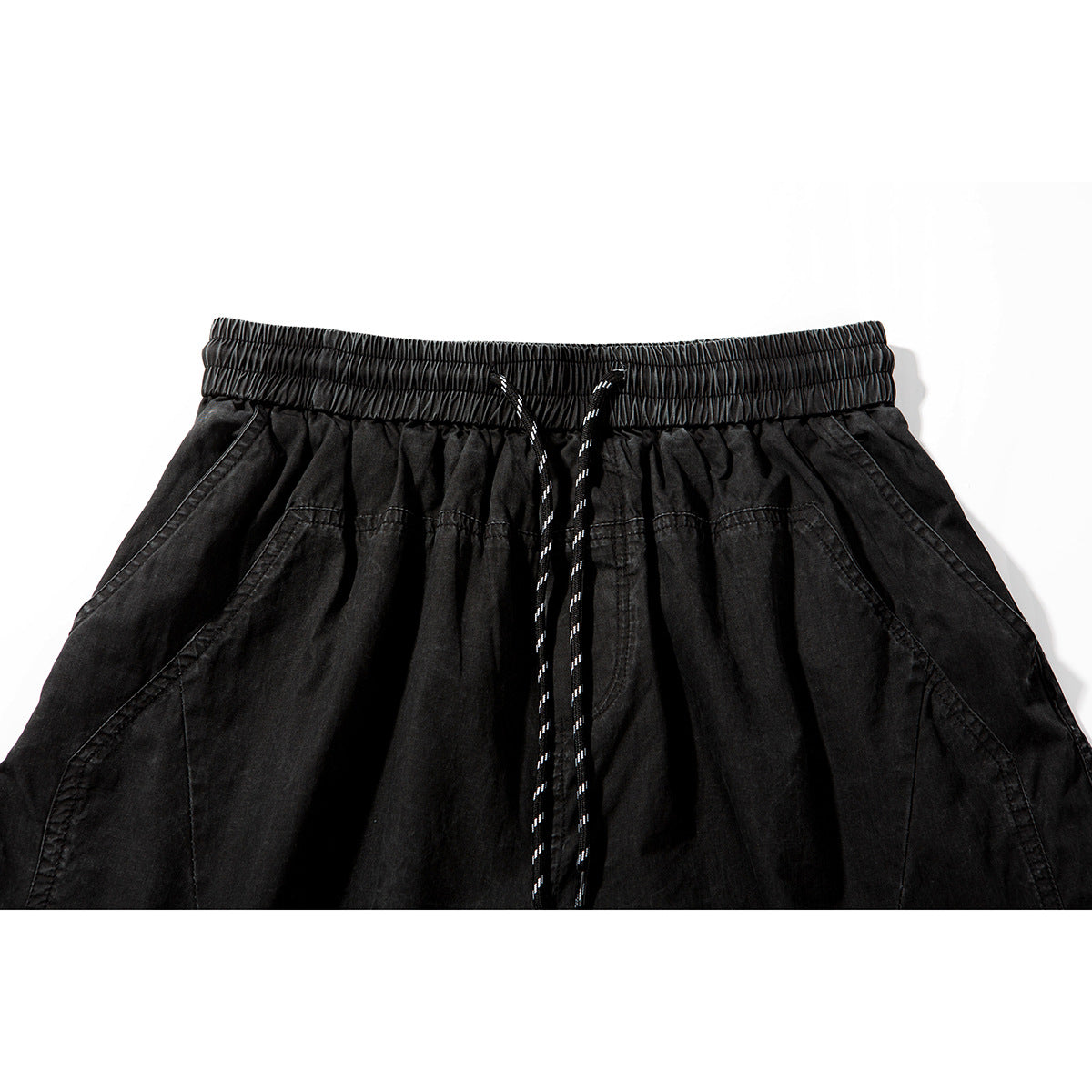 Close-up of black shorts showing the elastic drawstring waistband and angled seam details.