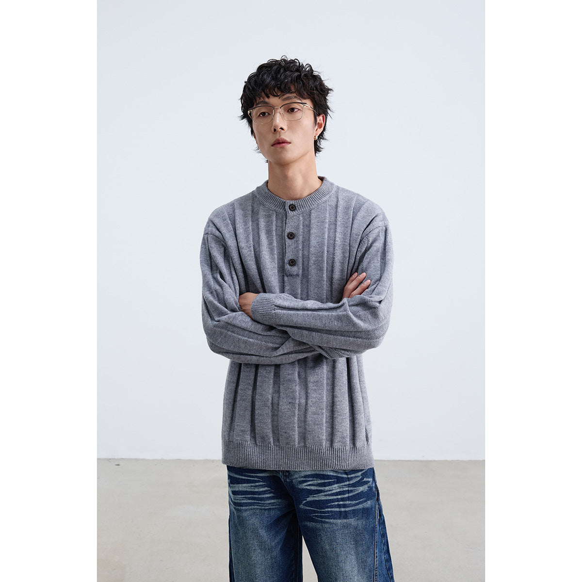 Model wearing a gray ribbed sweater with a round neck and three-button placket.