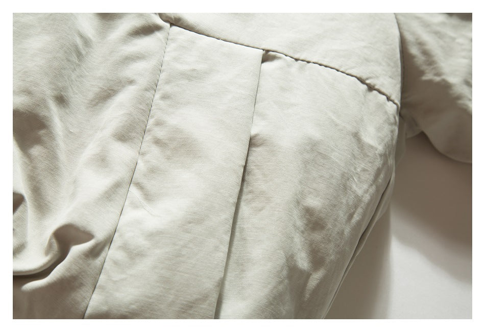 Close-up of a light beige jacket's stitched panels and seam.