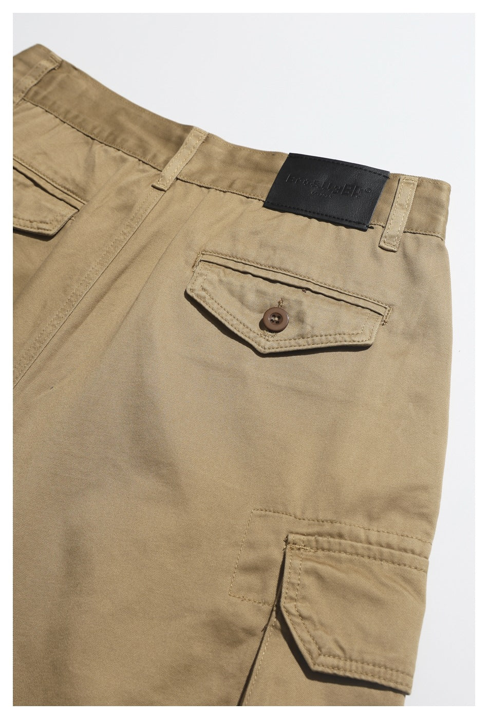 Close-up of the back of khaki cargo trousers, showing the waistband, buttoned pocket, and side cargo pocket.