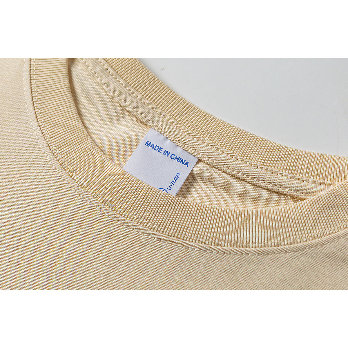 Close-up of a pale yellow T-shirt's ribbed crew neckline and inner label reading “MADE IN CHINA.”