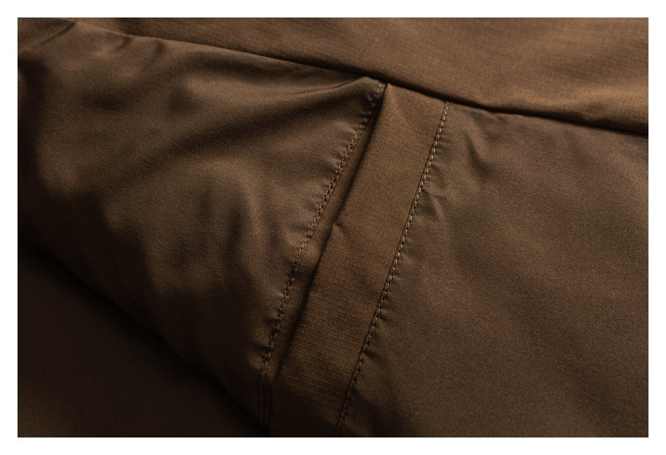 Close-up of a stitched panel seam on brown jacket fabric.
