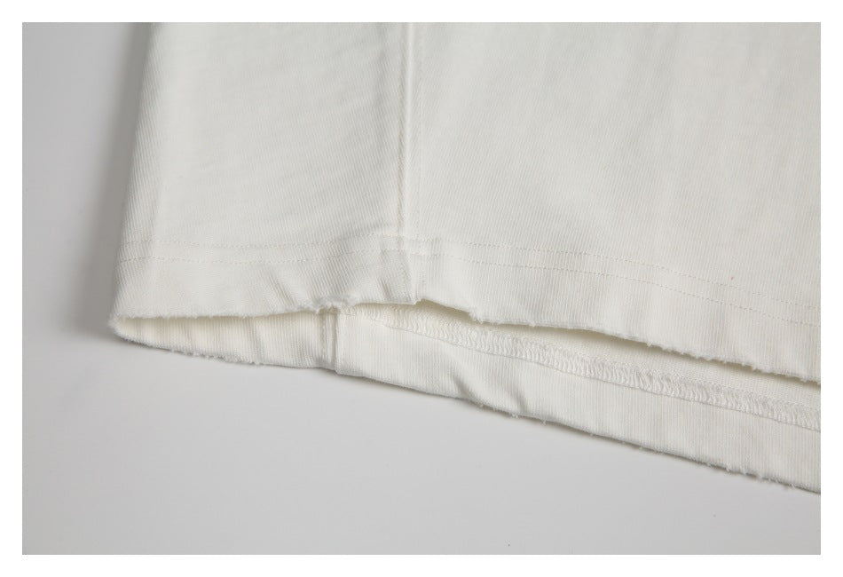 Close-up of the stitched bottom hem of an off-white T-shirt, showing the inside seam.
