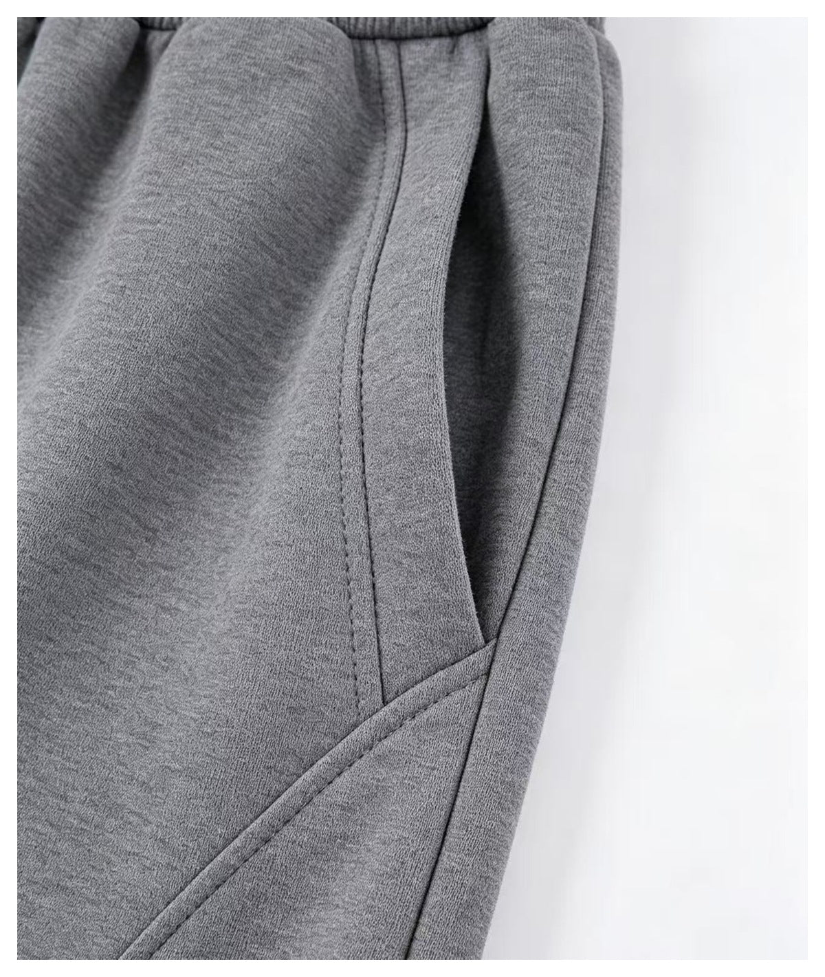 Close-up of a slanted front pocket and curved seam on the gray pants.
