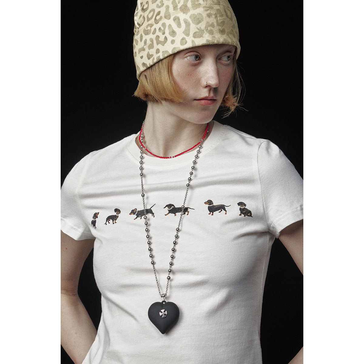 Close-up of a white T-shirt with a row of dachshund illustrations, worn by a model.