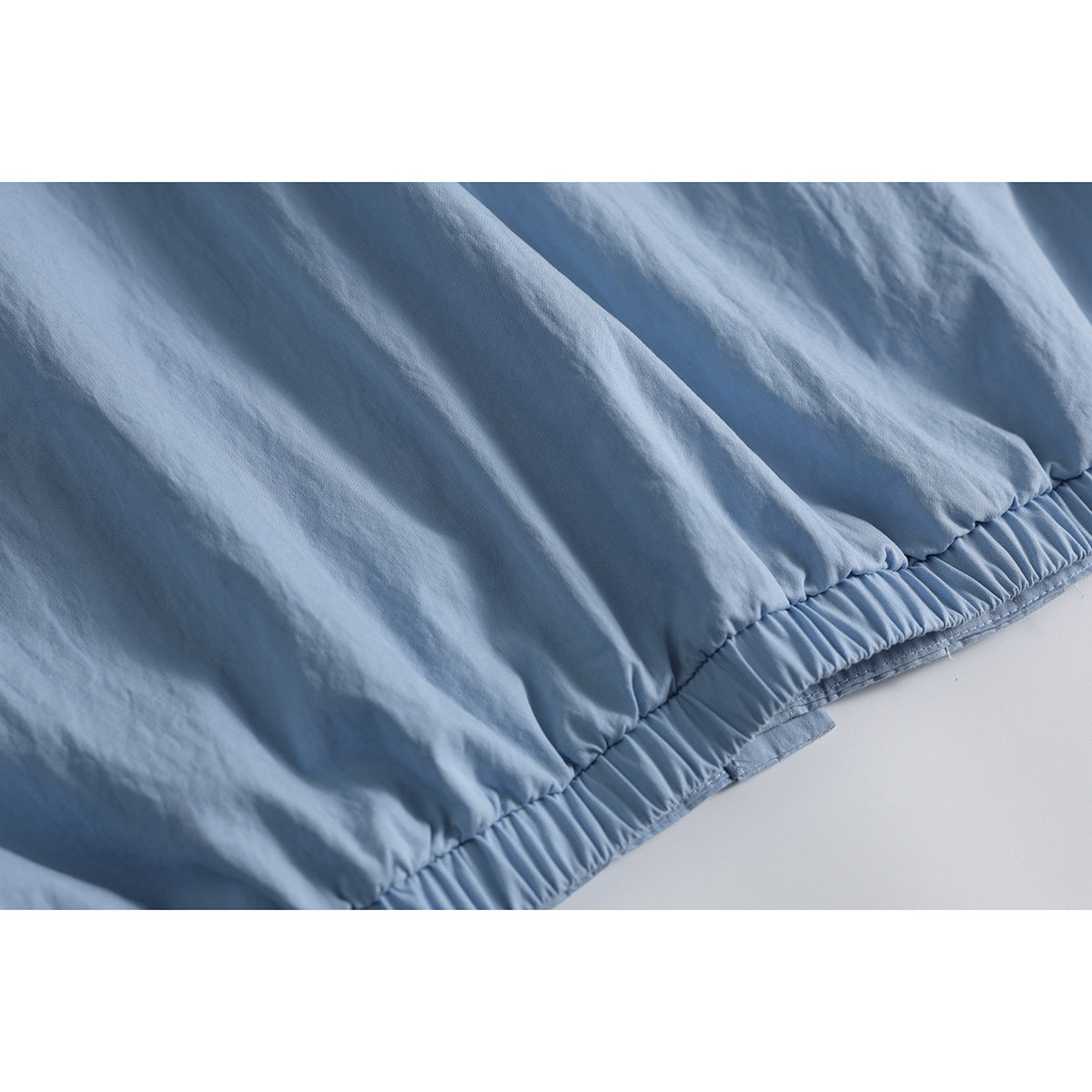 Close-up of the gathered elastic hem on a light blue shirt.