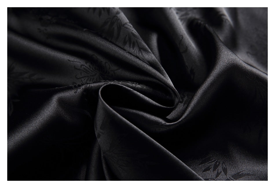Close-up of softly draped black fabric with a subtle floral pattern and smooth sheen.