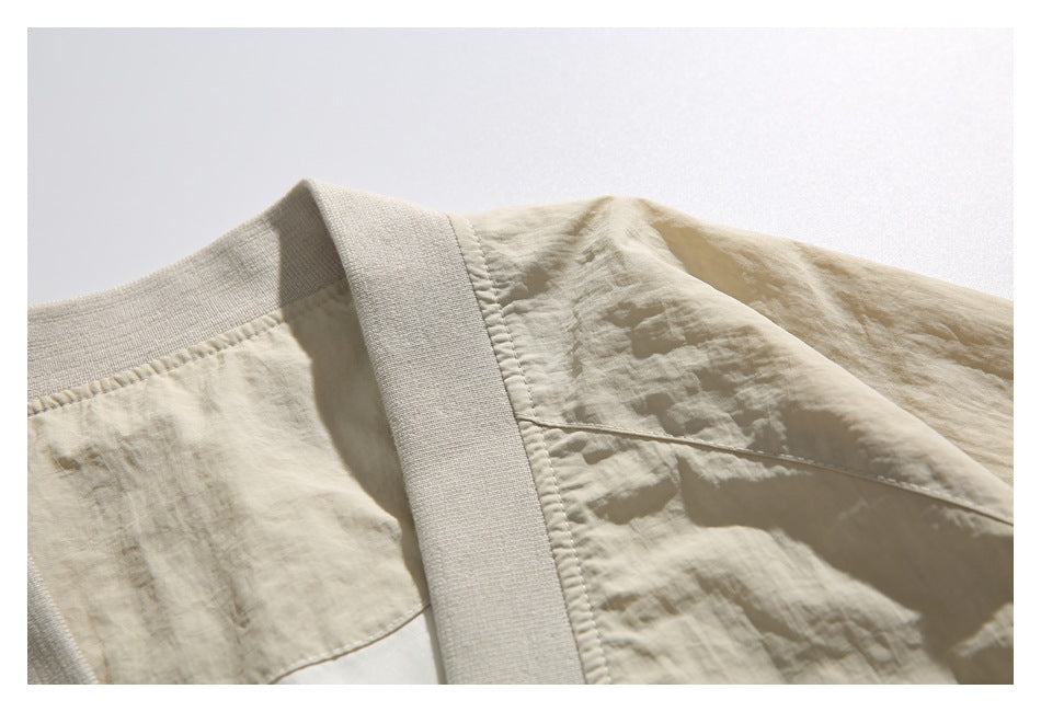 Close-up of a light beige jacket collar, shoulder seam, and ribbed neckline trim.