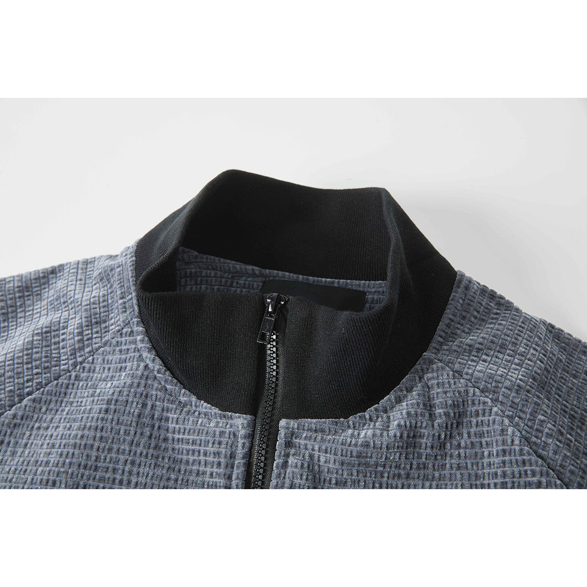 Close-up of a gray textured jacket’s black stand collar and front zipper.
