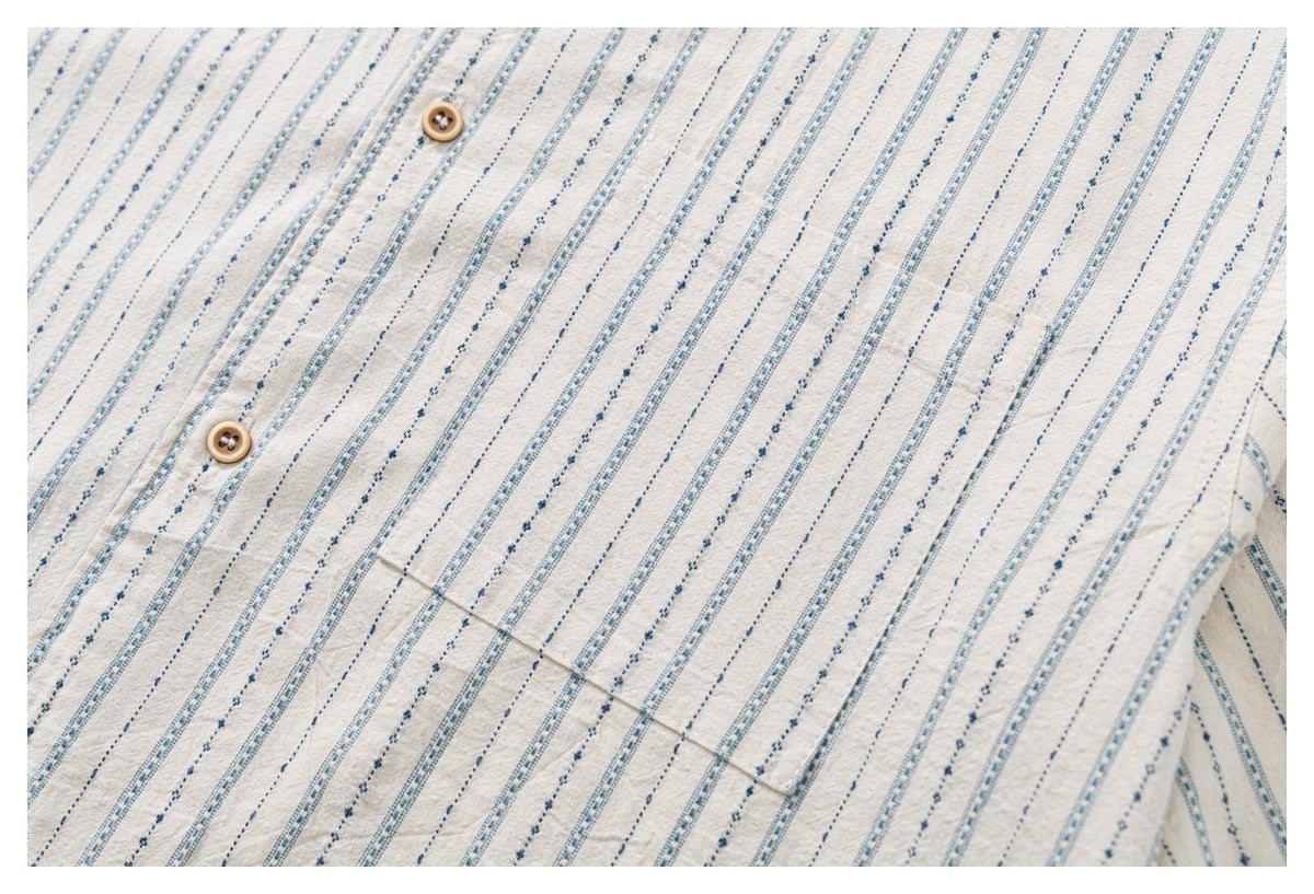 Close-up of the off-white shirt's striped fabric, wooden buttons, and chest pocket.