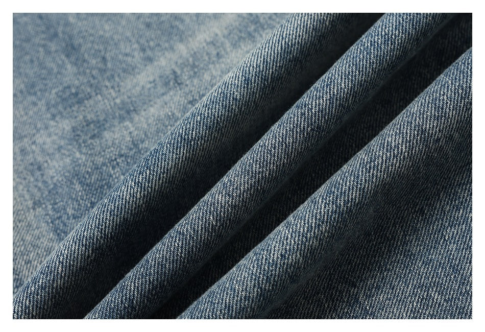 Macro view of blue denim fabric folded to show its faded texture and weave.